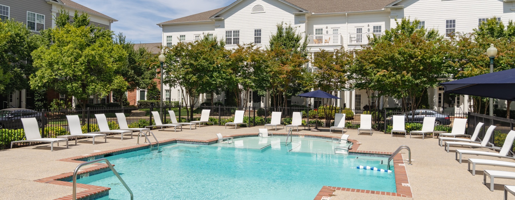 wide view of uniquely shaped swimming pool showing multiple reclining seats, spacious walking areas & nearness to the property