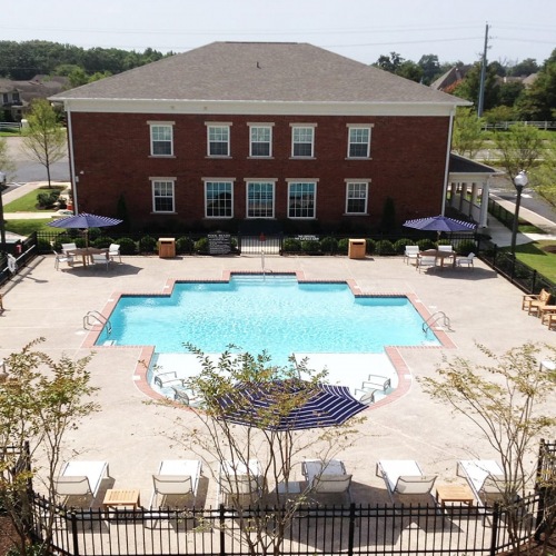 wide view of uniquely shaped swimming pool showing multiple reclining seats, spacious walking areas & nearness to the property